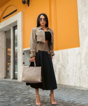 Woman in stylish attire poses confidently outdoors.