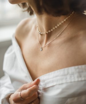 woman in white off shoulder shirt wearing silver necklace