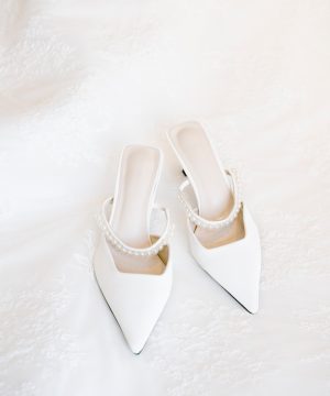 A pair of white shoes sitting on top of a bed