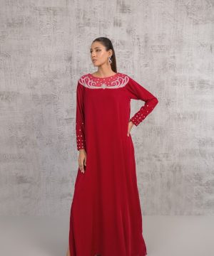 A woman in a long red dress standing in front of a wall