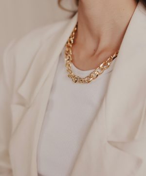 A woman wearing a white jacket and a gold necklace