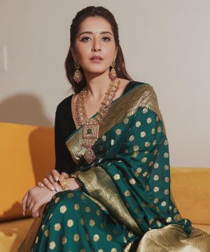 A woman sitting on a couch wearing a green and gold sari