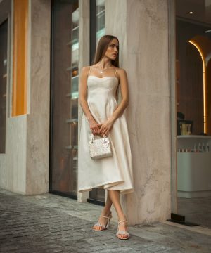 Woman in elegant dress poses outdoors.
