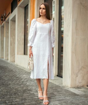 Woman walks confidently in a stylish white dress.