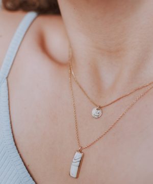 woman wearing gold necklace with silver pendant